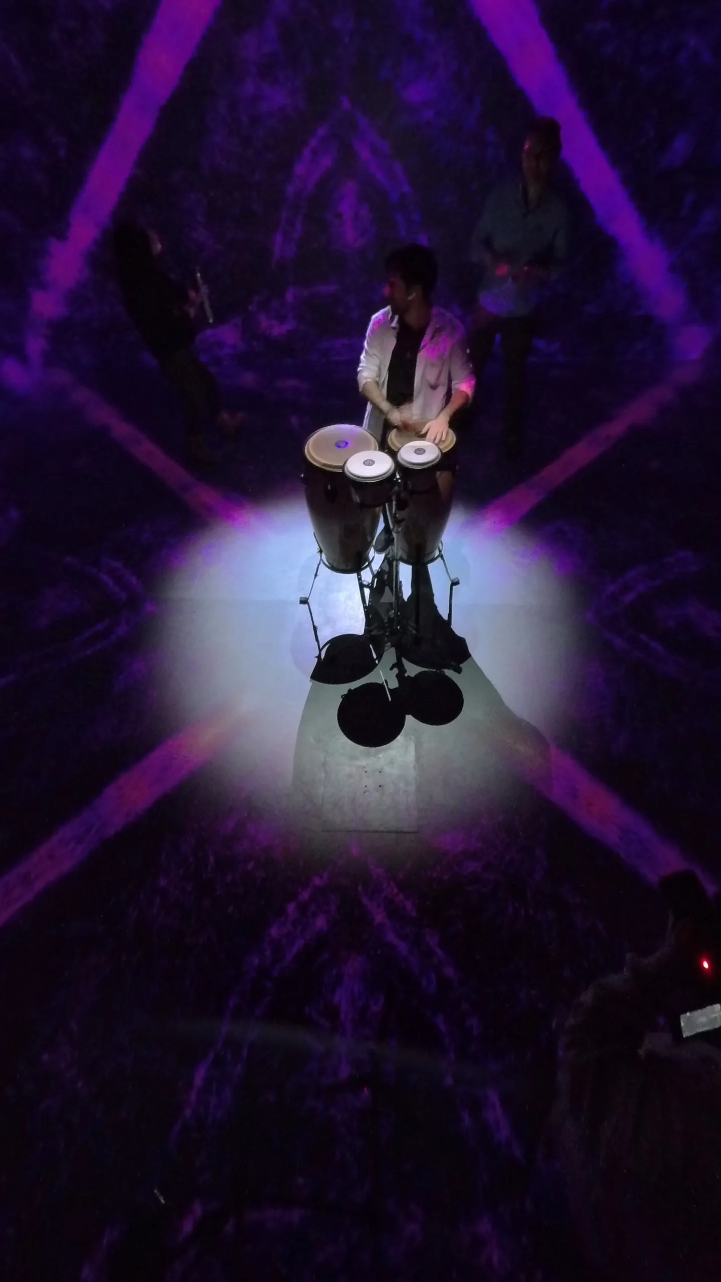 Seen from above: the percussionist at the centre of a violet kaleidoscopic floor