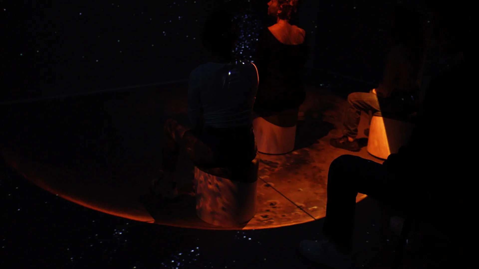 Visitors seated on the Martian surface, the terrain carried across the floor